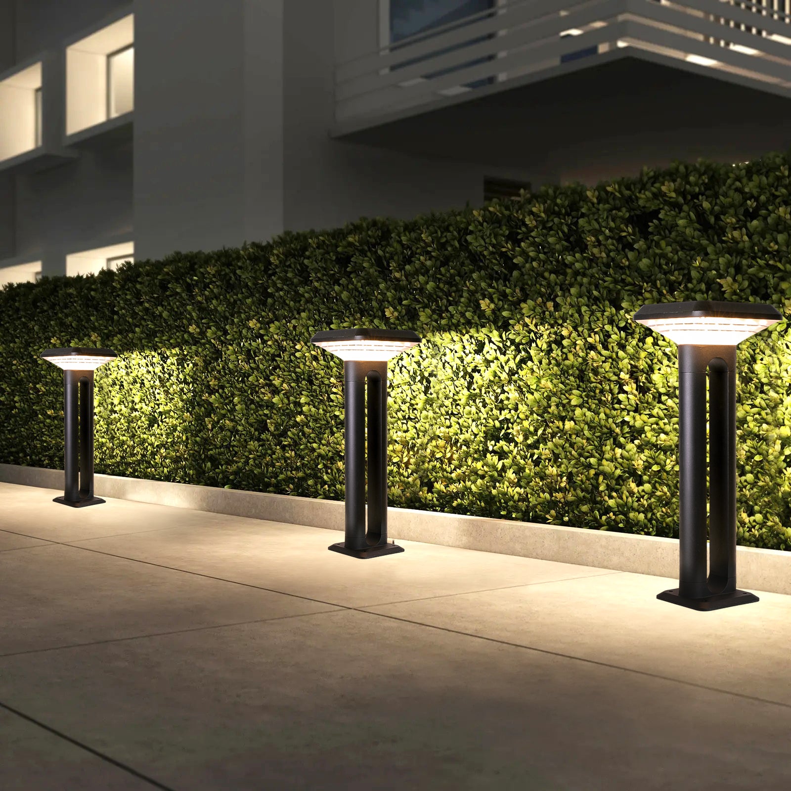 Ark Series Solar Lawn Light CPD1201 lighting a hedge pathway beside a modern residential building